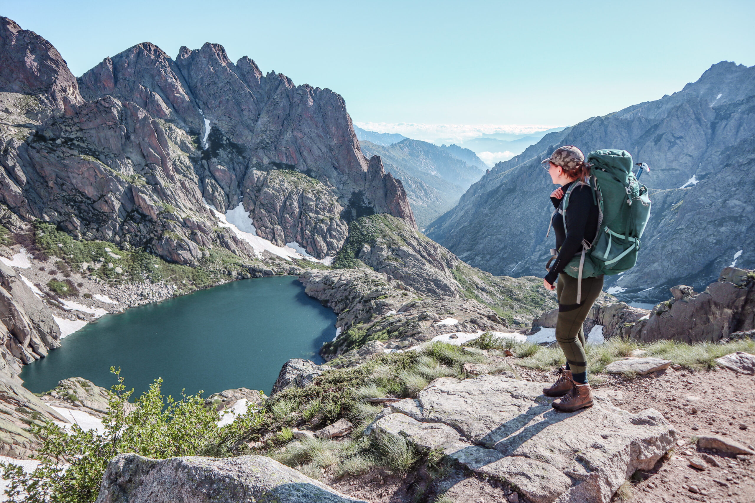 Woman hiking the long distance hike in Corsica called the GR20. A long hike with a heavy backpack. Hiking for two weeks with the most incredible views over the mountains.